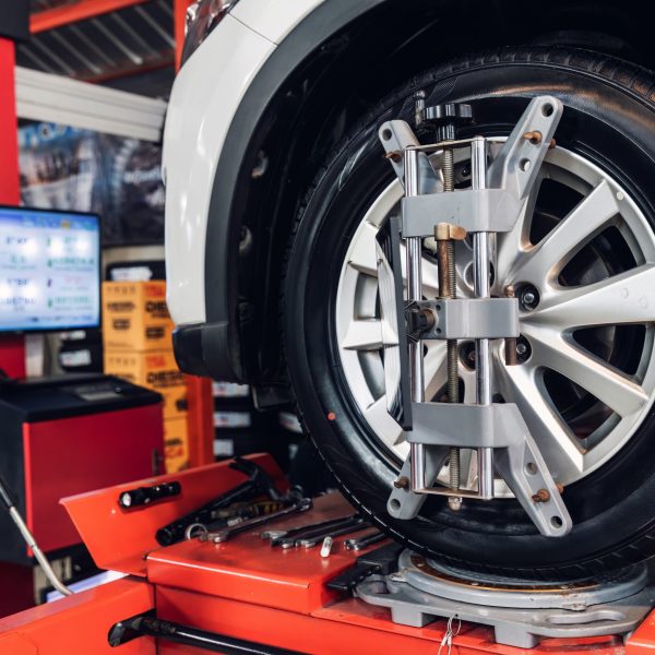 Car wheel centering machine adjustment. Auto service mechanic installing wheel alignment sensor on tire during vehicle suspension alignment adjustment