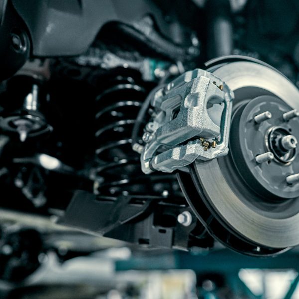 Disc brake of the vehicle for repair, in process of new tire replacement. Car brake repairing in garage.Suspension of car for maintenance brakes and shock absorber systems.Close up.