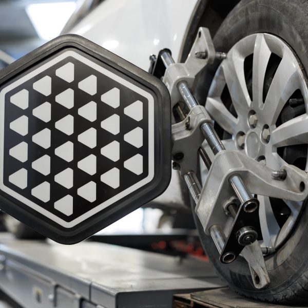 Vehicle inside garage workshop for auto camber toe check fixing work. Car wheel balancer calibrate with laser reflector attach on each tire to center driving adjust